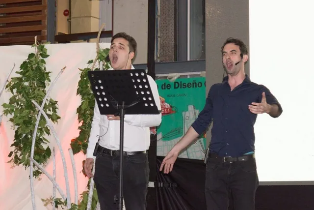 Dos personas presentan una actividad con micrófonos.