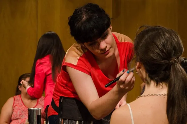 Una maquilladora prepara a una participante antes de salir.