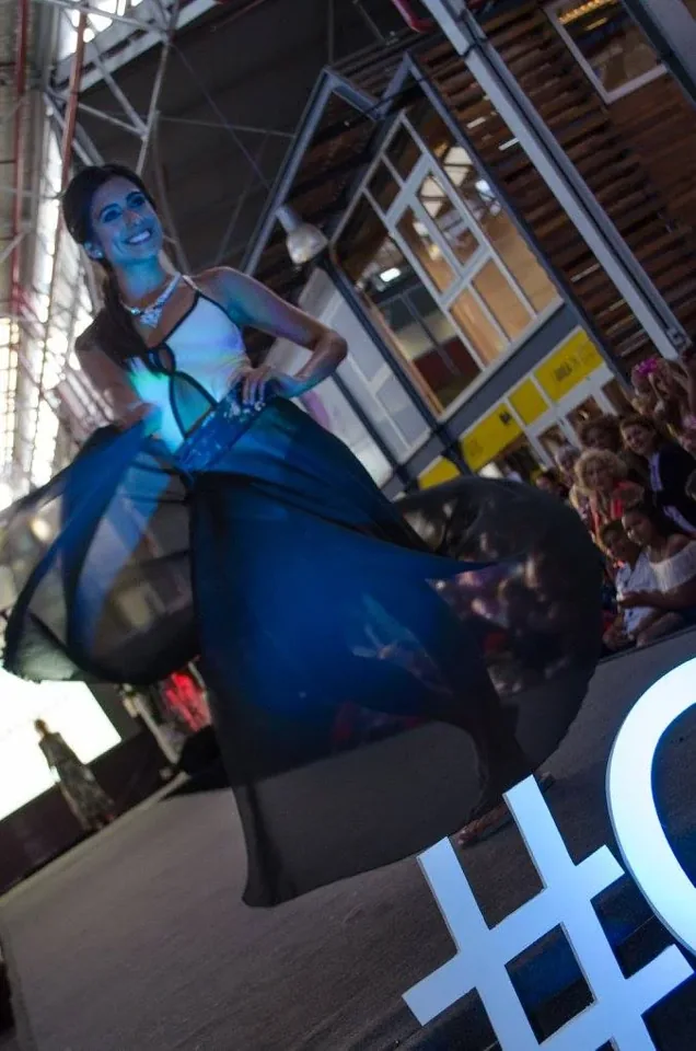 Una participante presenta una prenda azul durante el desfile.