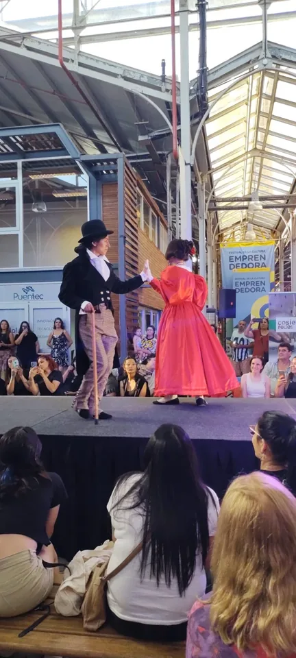 Dos participantes presentan prendas sobre el escenario.